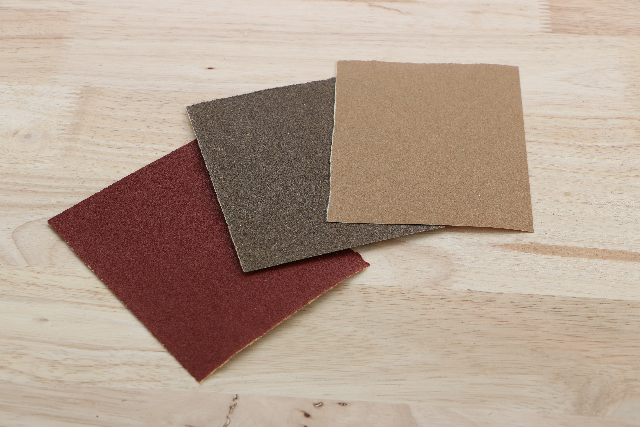 Three sheets of different grit sandpaper.