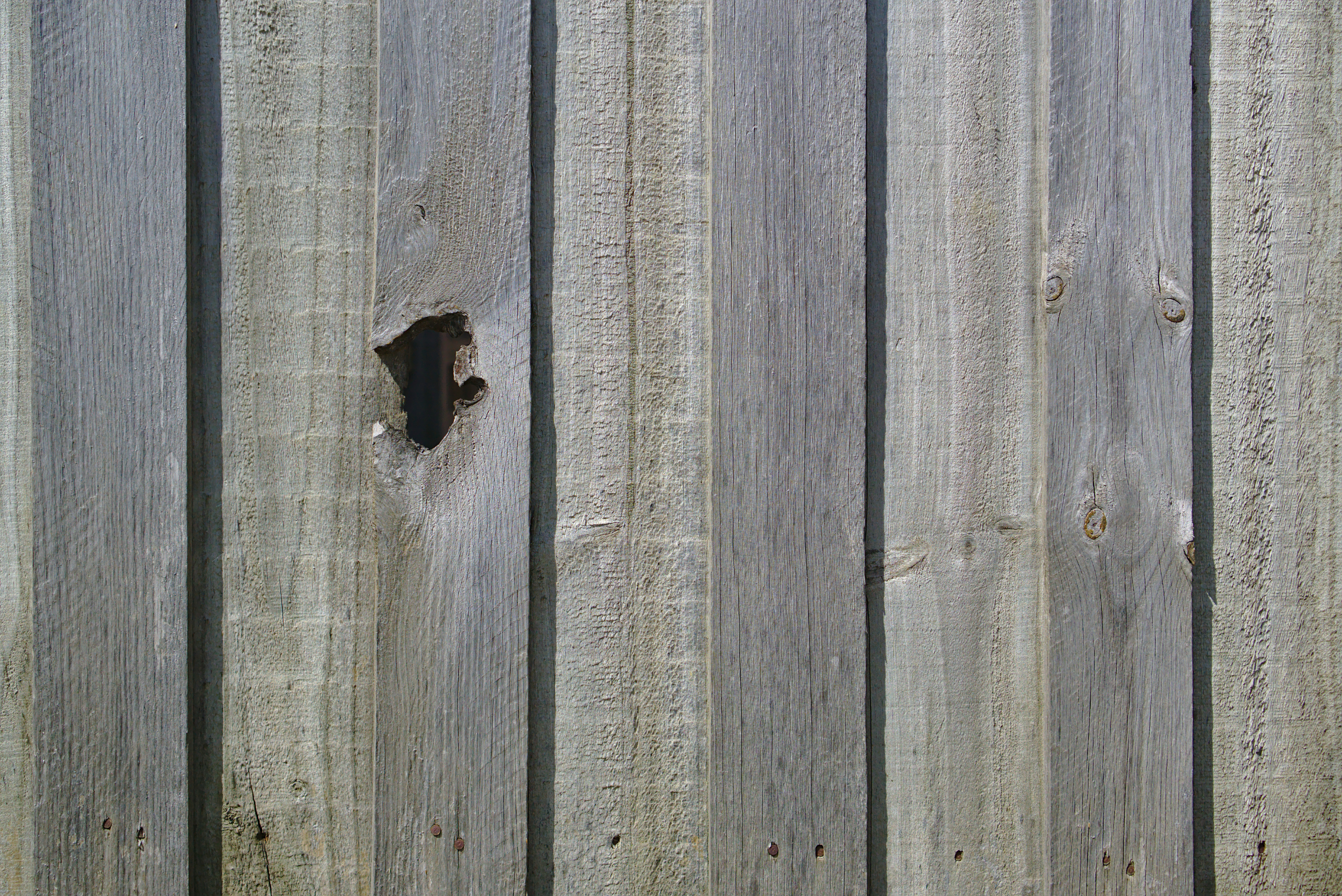 Wooden fence with hole in one of the boards.