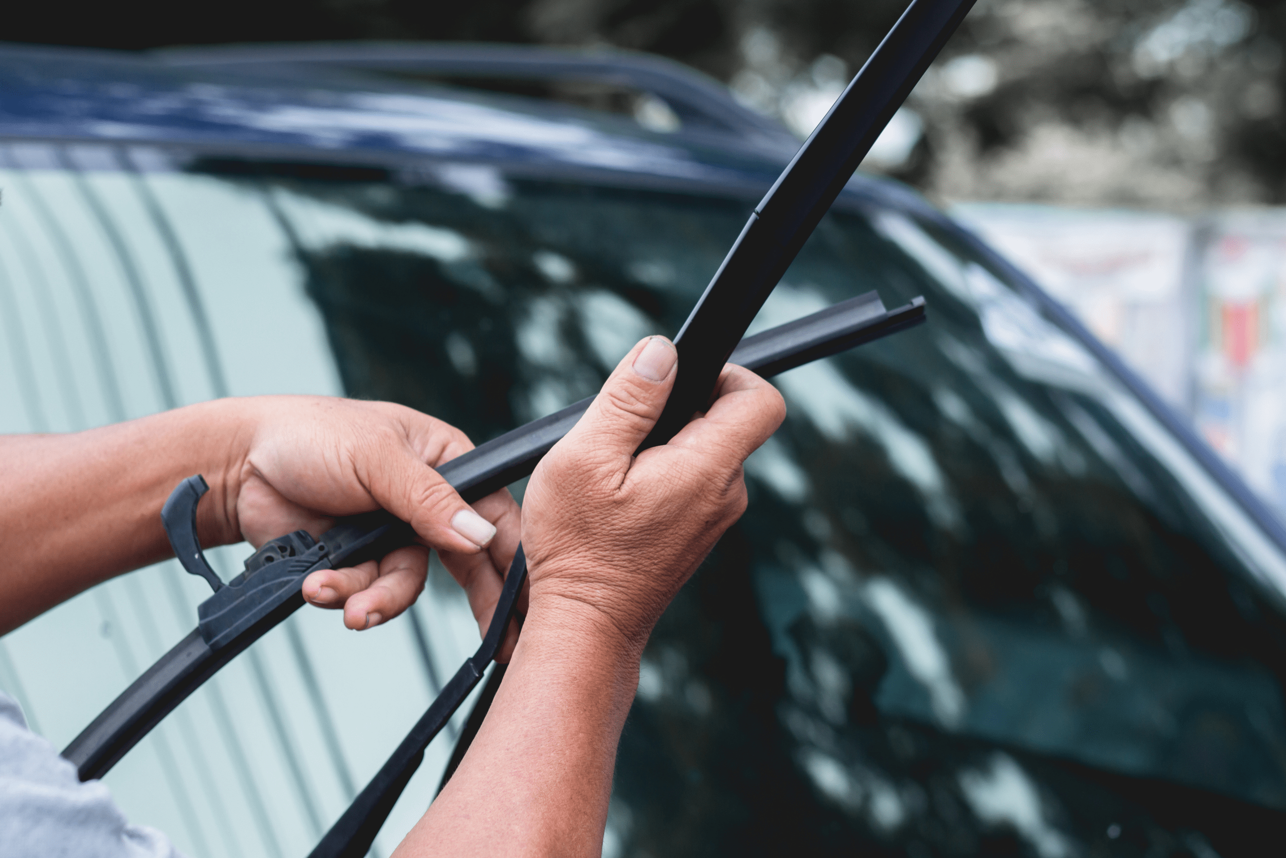 Person's hands installing new windshield wiper blades.