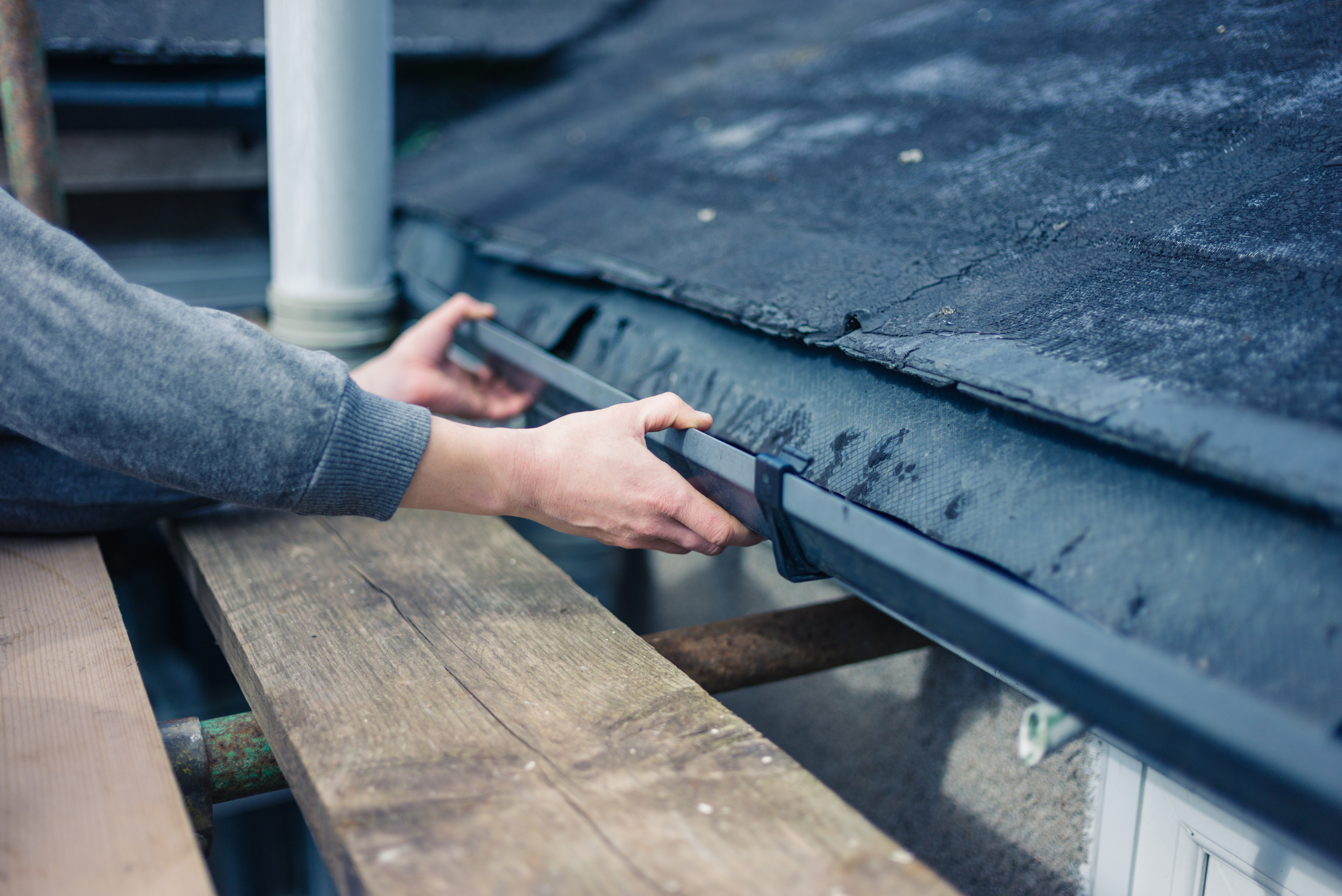 Person adjusting home gutters.