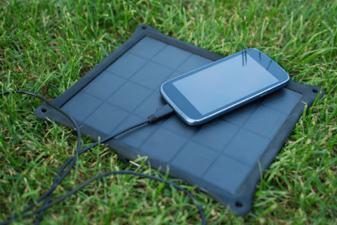 Phone on top of a solar panel that it's plugged into.