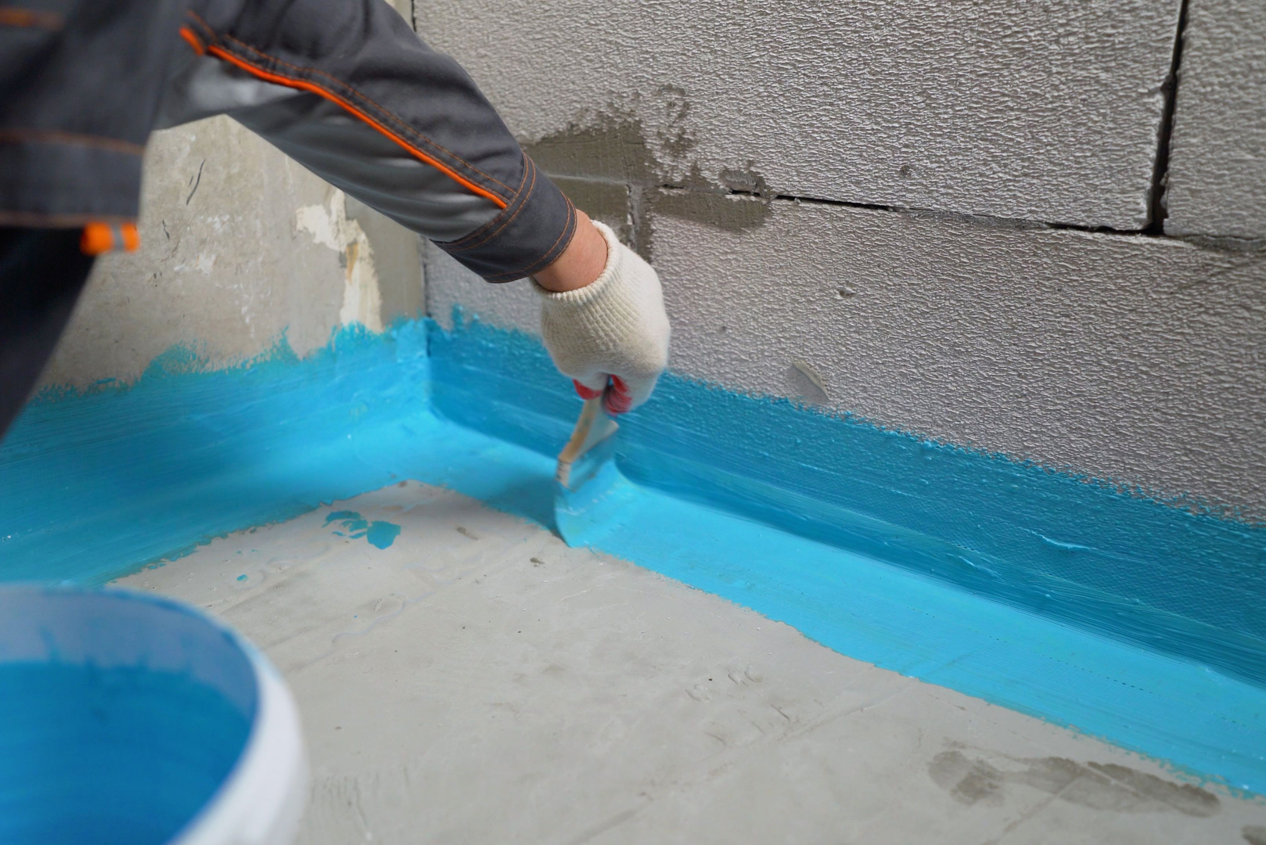 Sealing basement walls with blue coating.