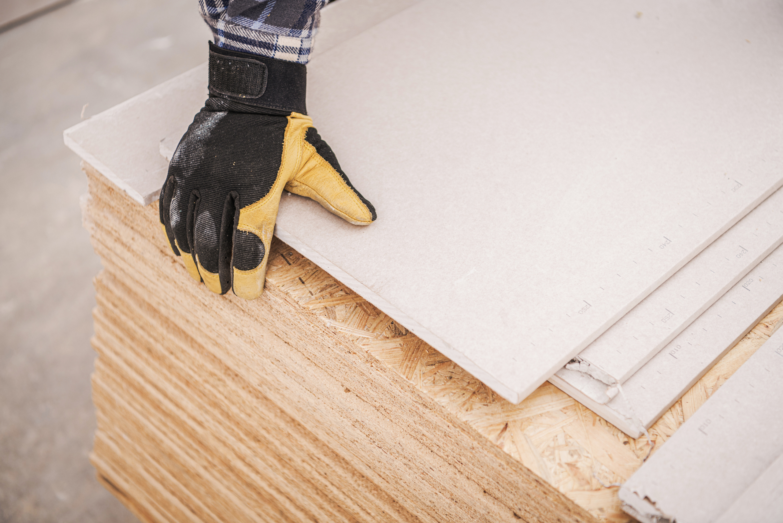 Person wearing gloves grabbing plywood.