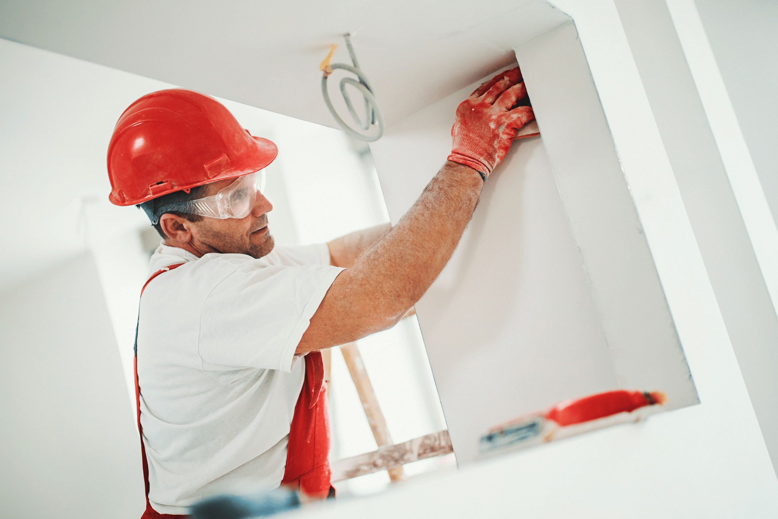 Worker sanding a drywall corner.