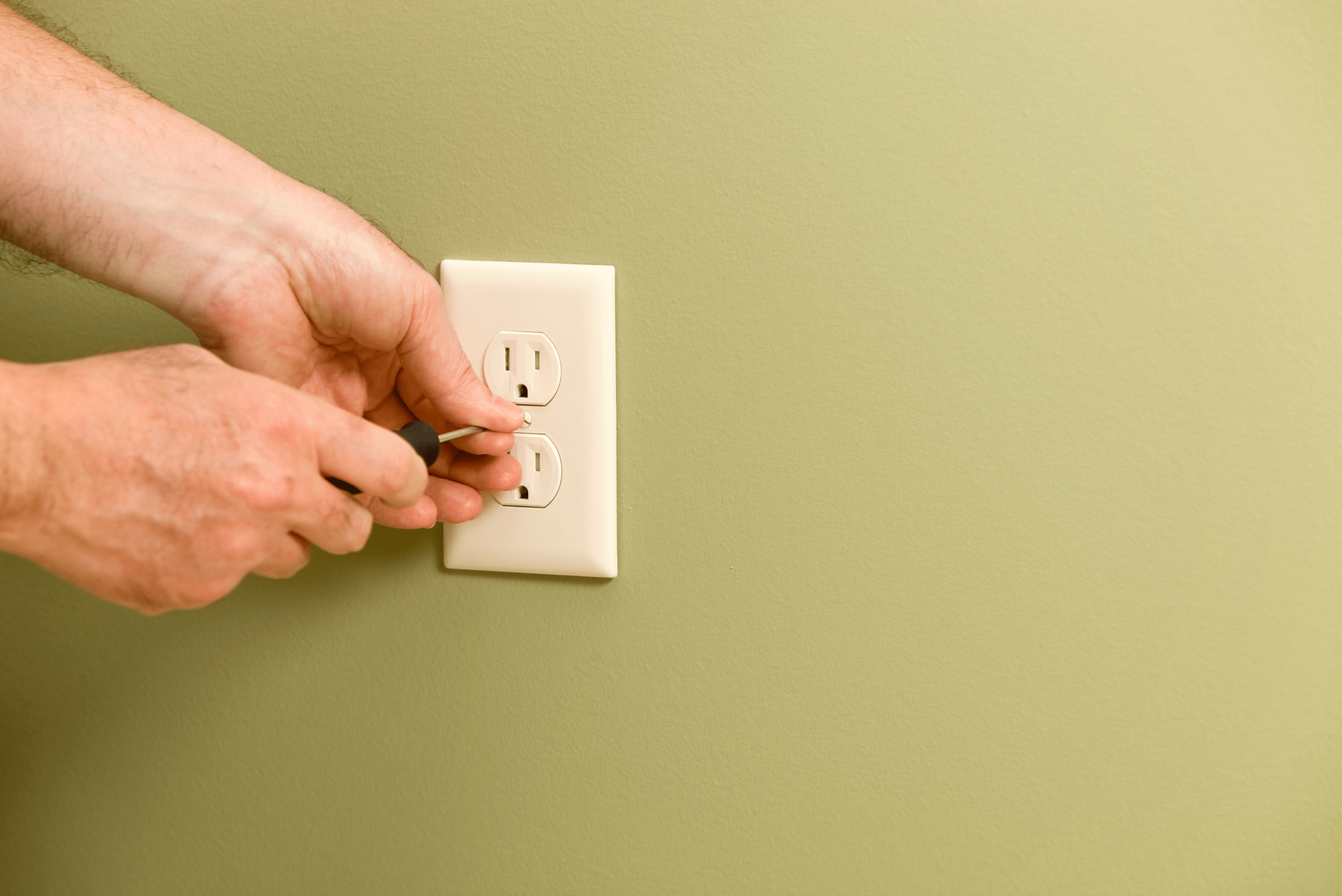 Hands installing outlet cover.