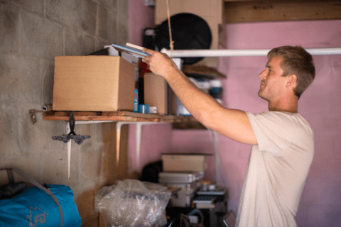 Person removing items from garage shelf.