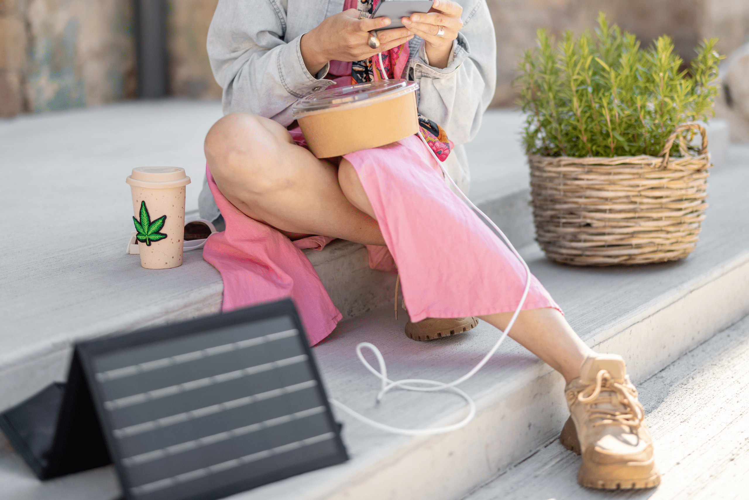 Woman using a solar panel with stand to charge phone.