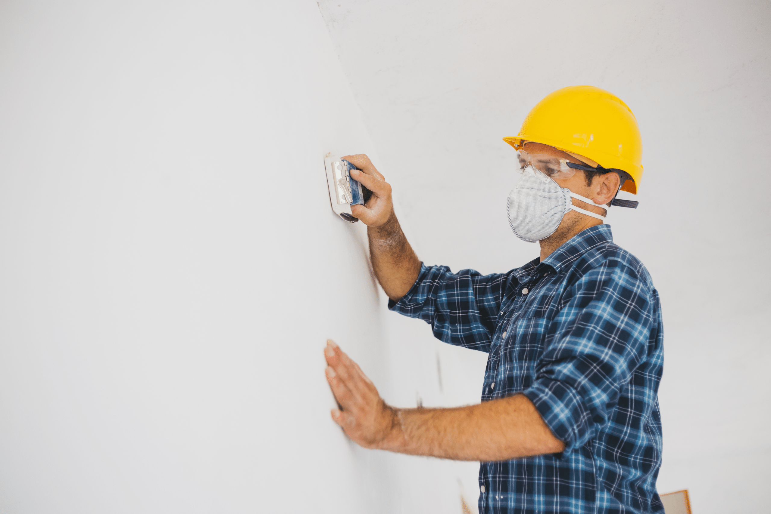 Man sanding and feeling drywall.