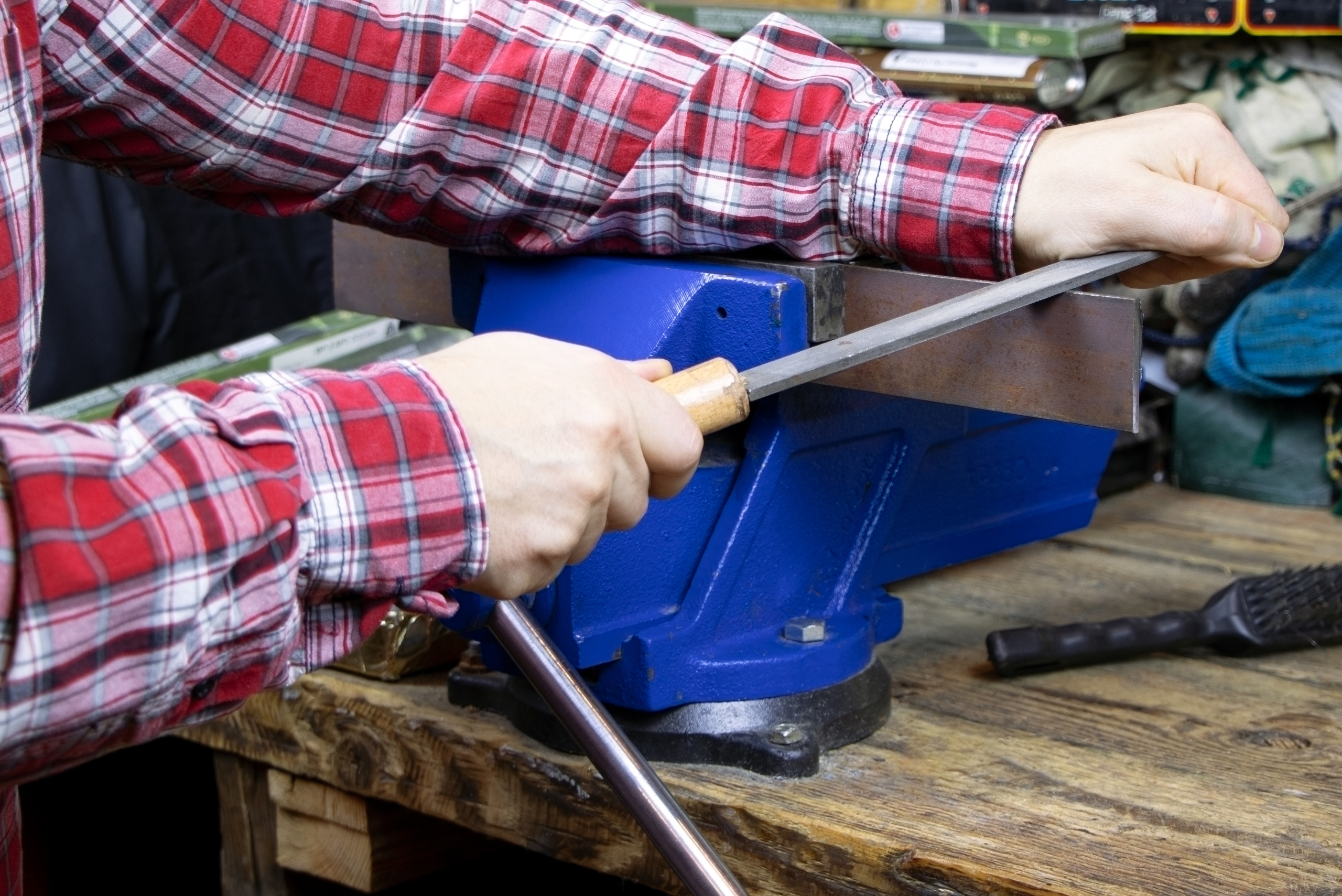 Person using a blue bench vise.