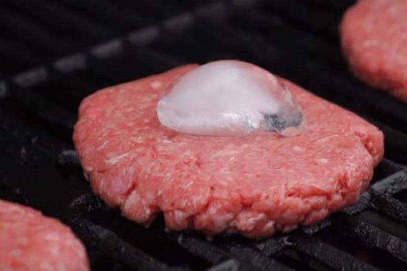 Ice cube on a raw burger being cooked.