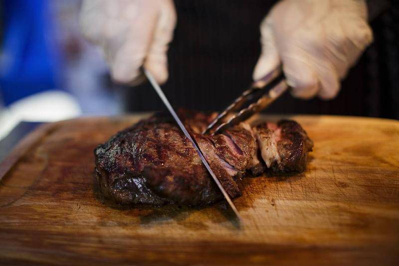 Person cutting a piece of steak.