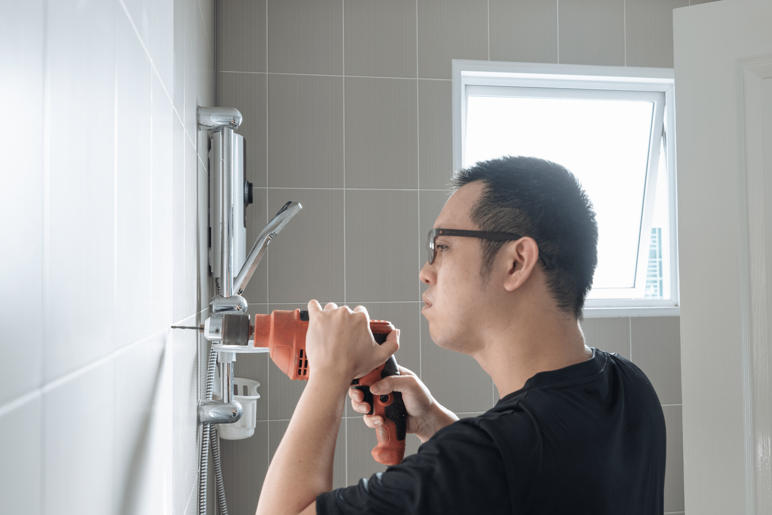 Man drilling holes for towel rack.