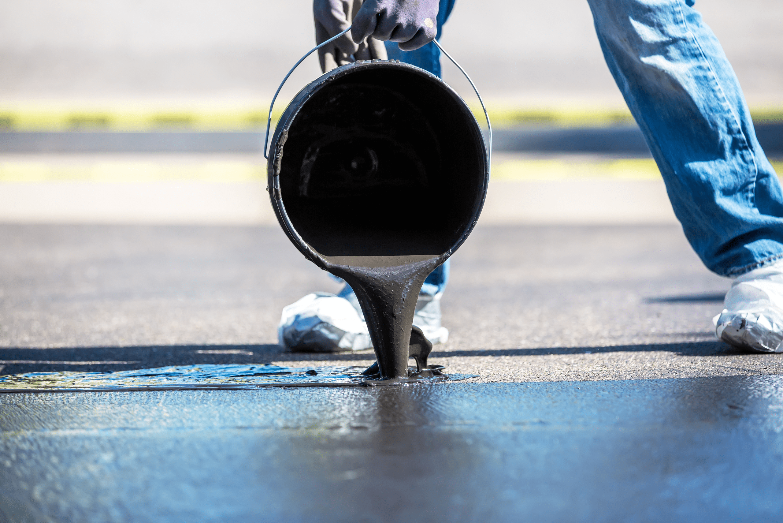 Pouring sealant onto driveway.