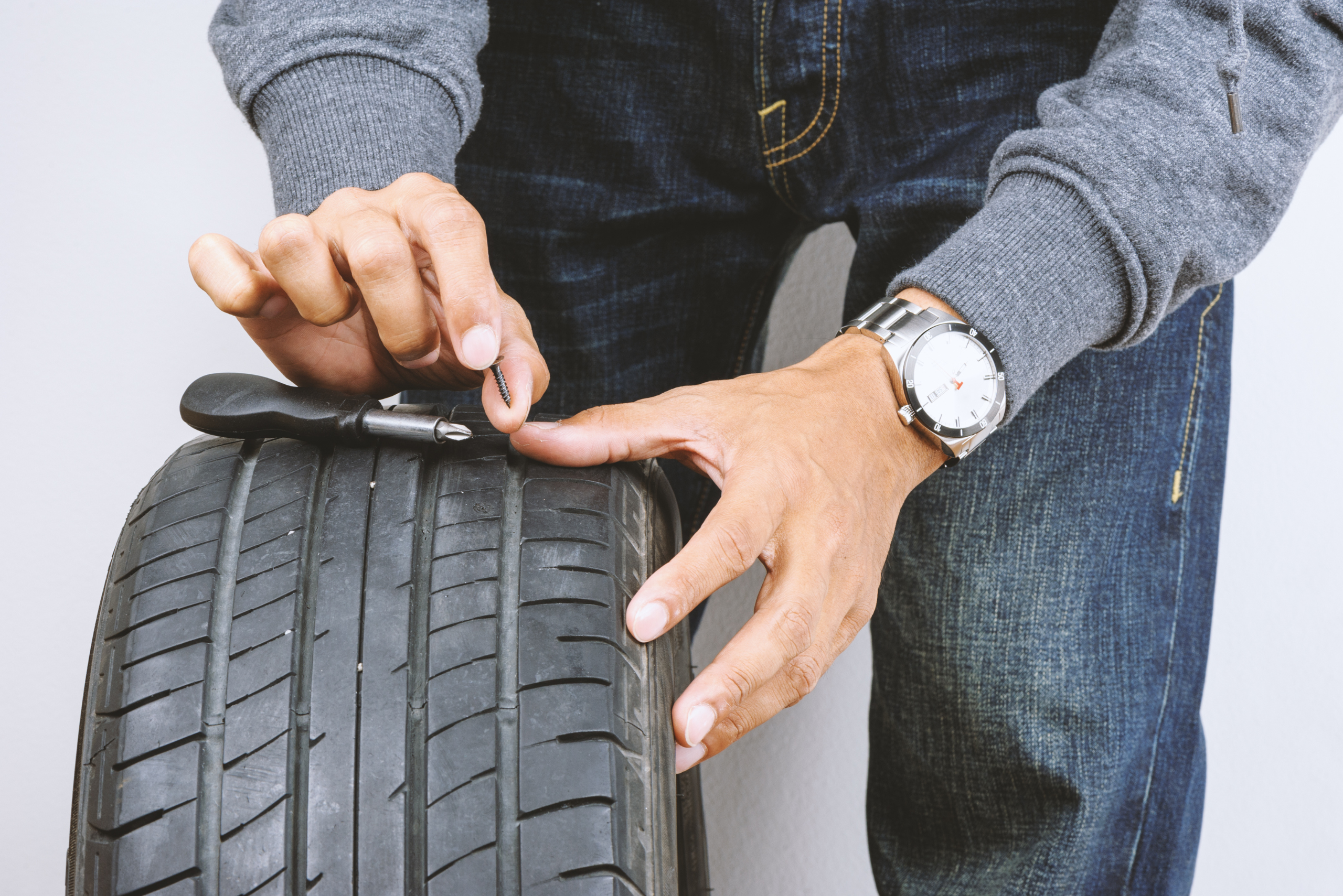 Man using a tire plug kit.