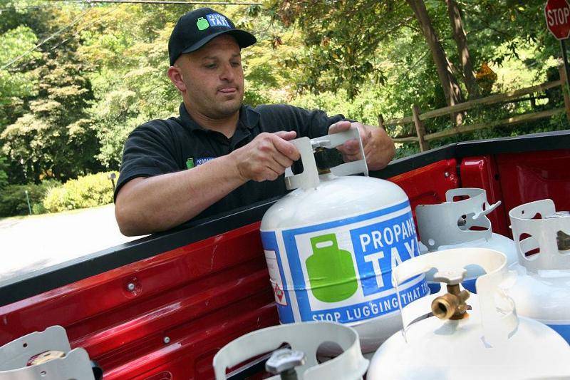 Man grabbing propane tank from truck.