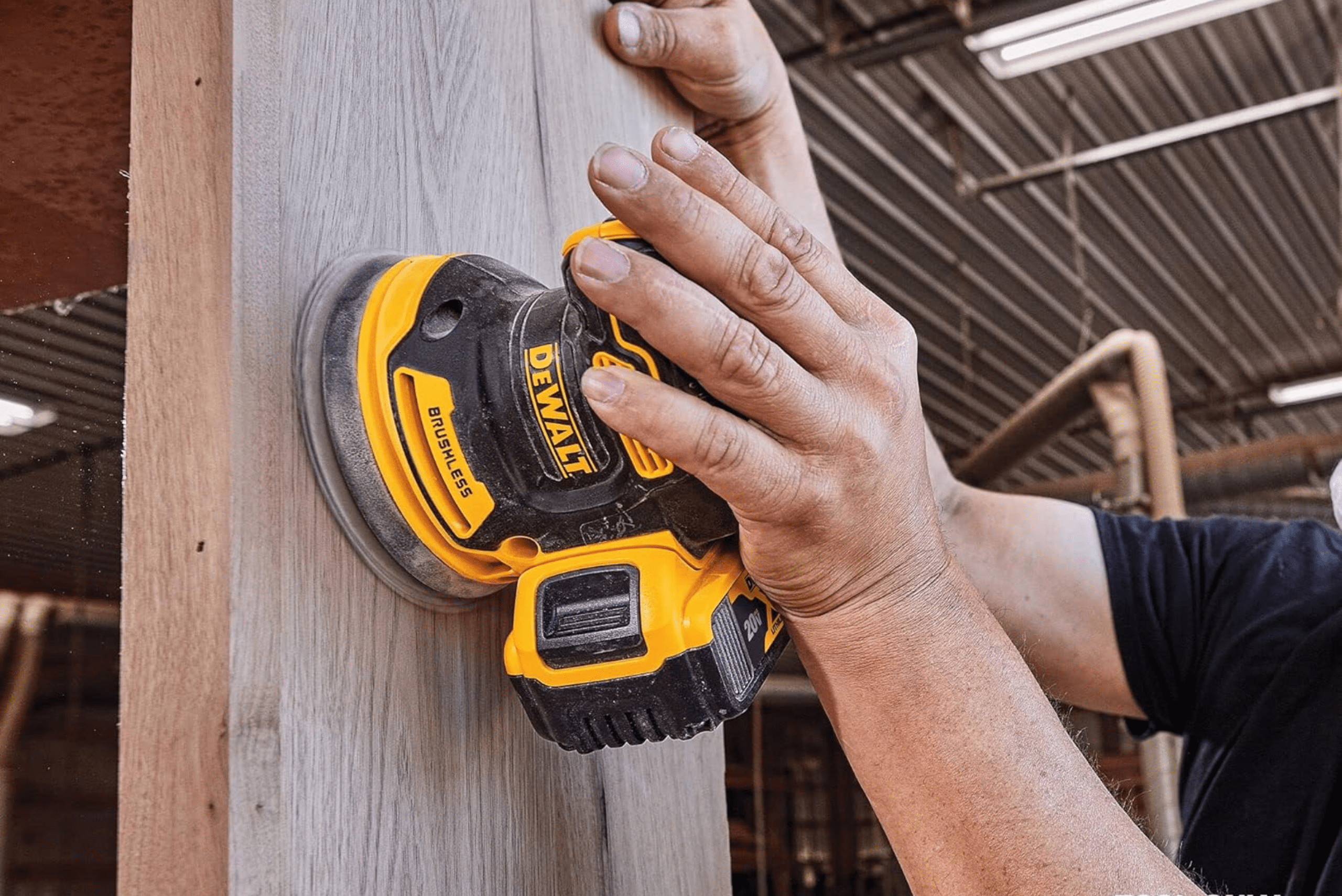 Orbital sanding being used by a man on wood.