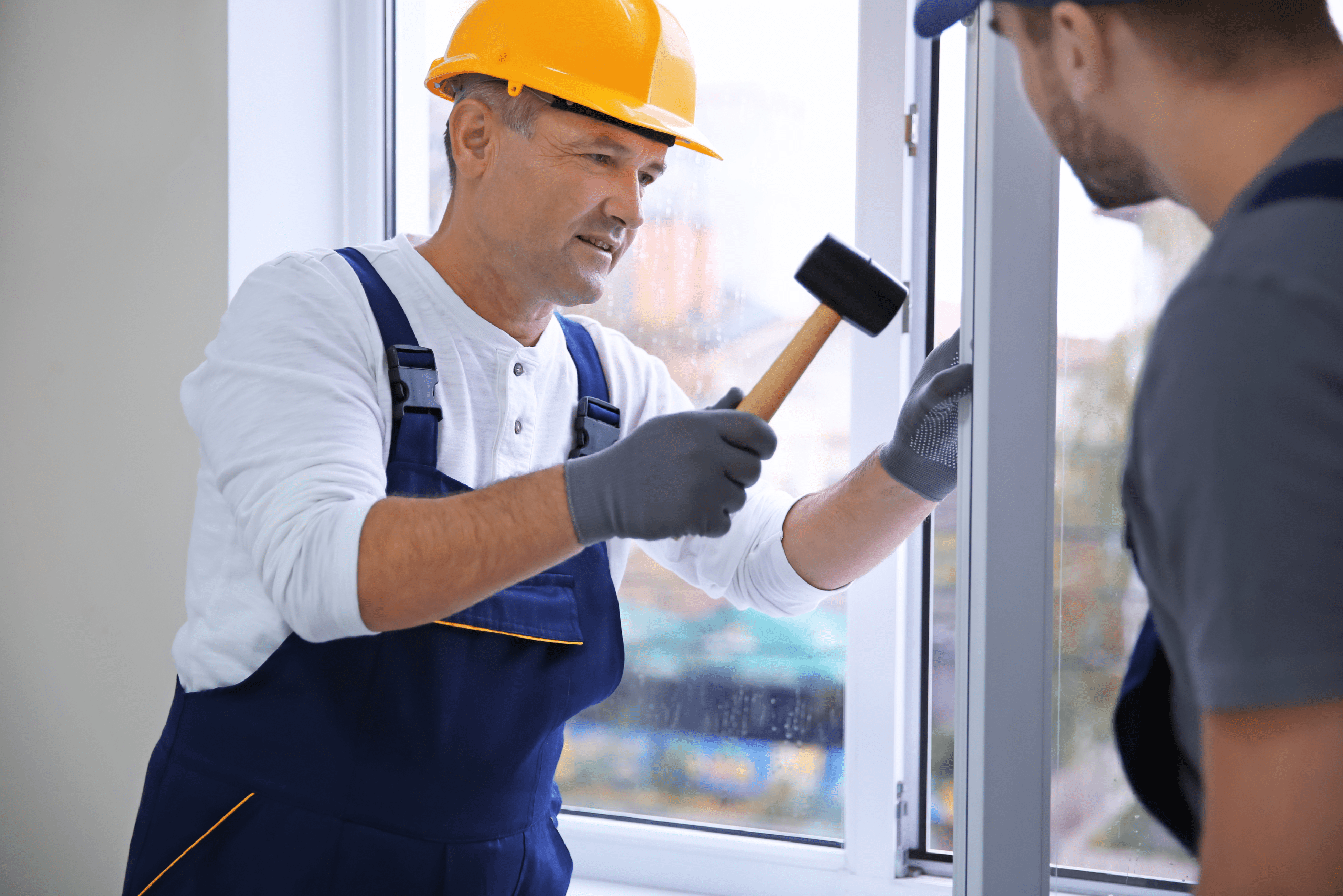 Worker using a mallet to tap on a window.