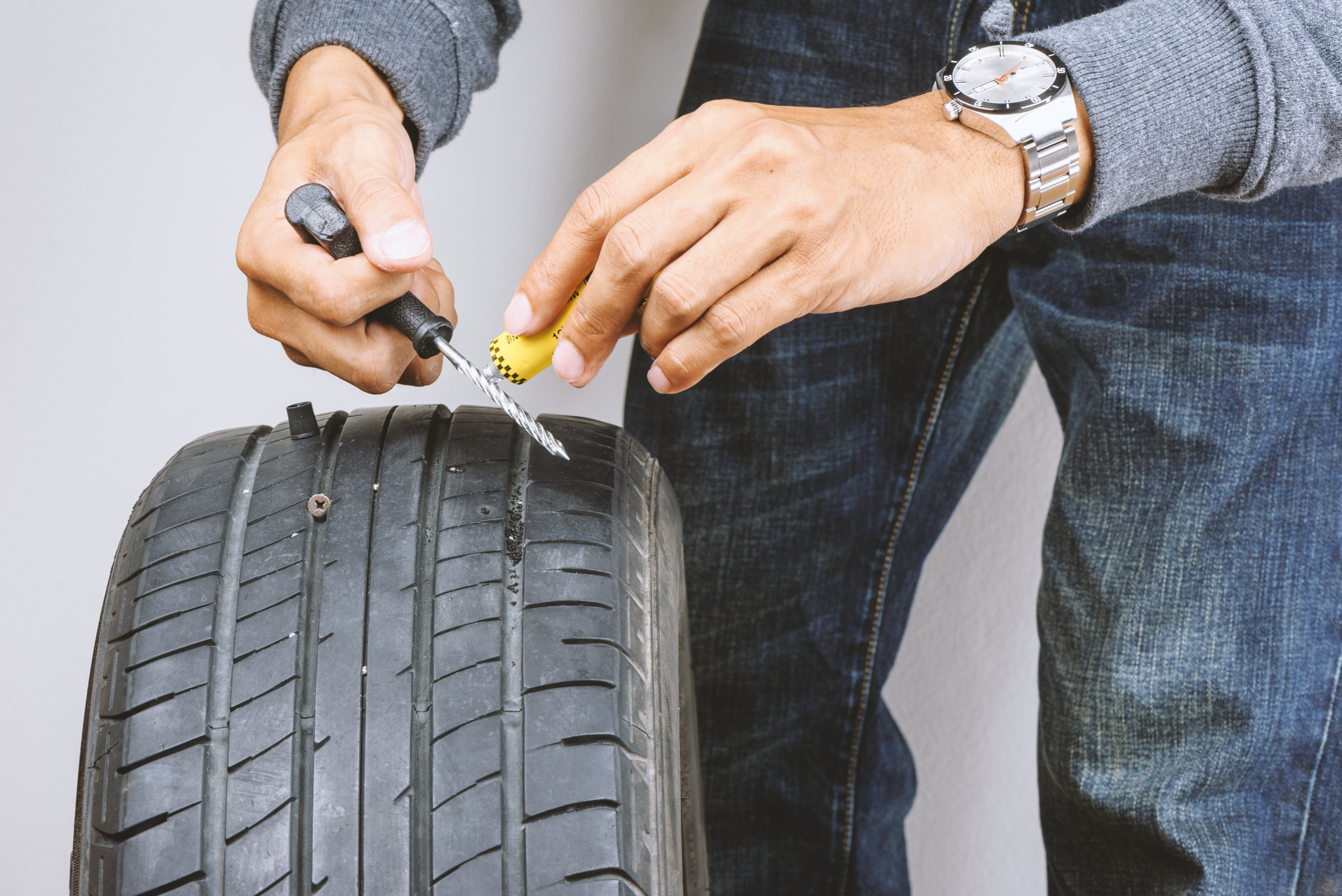 Man using a tire plug kit.