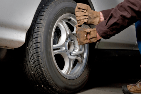 Man removing lug nuts off a vehicle's wheel.