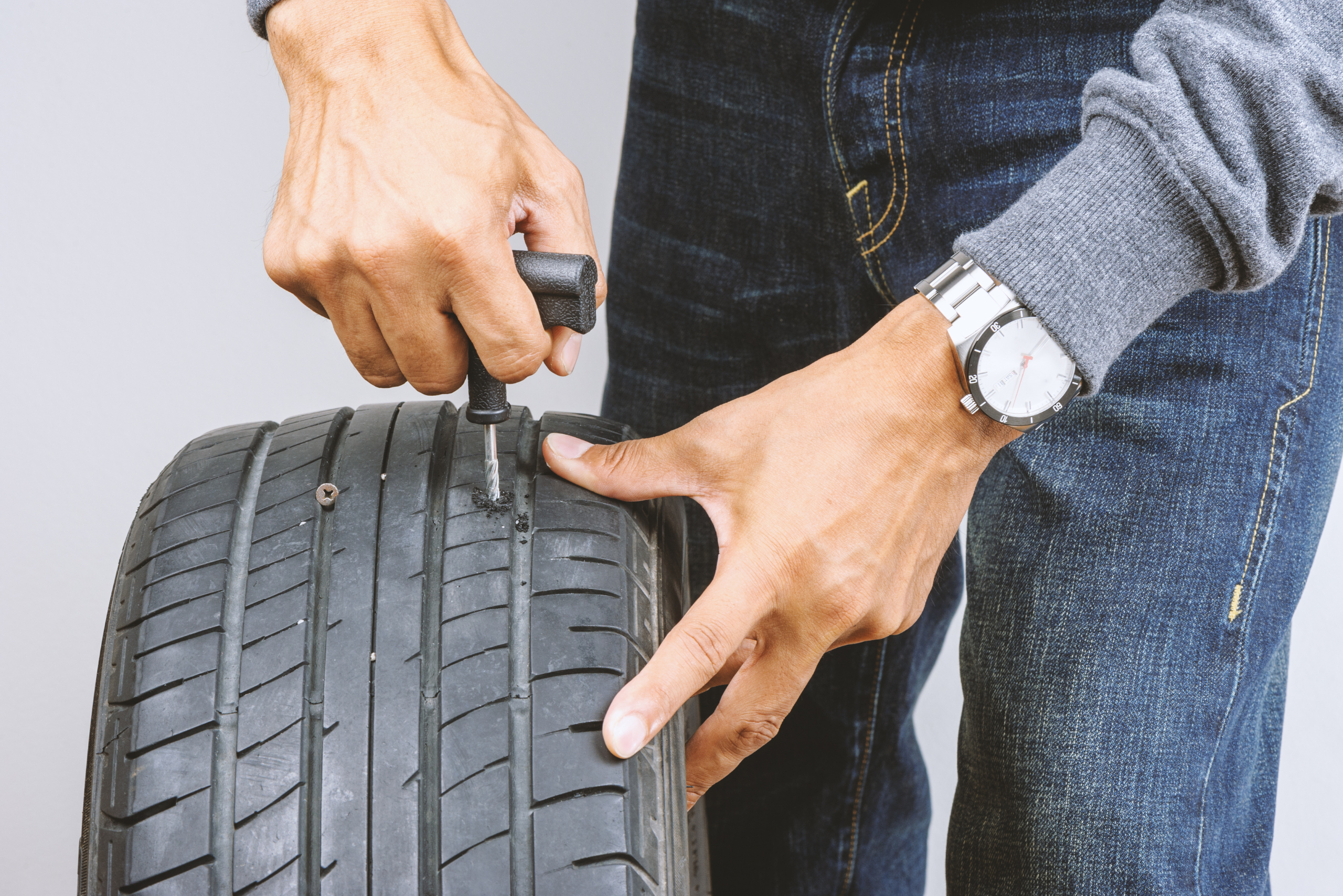 Man using a tire plug kit.