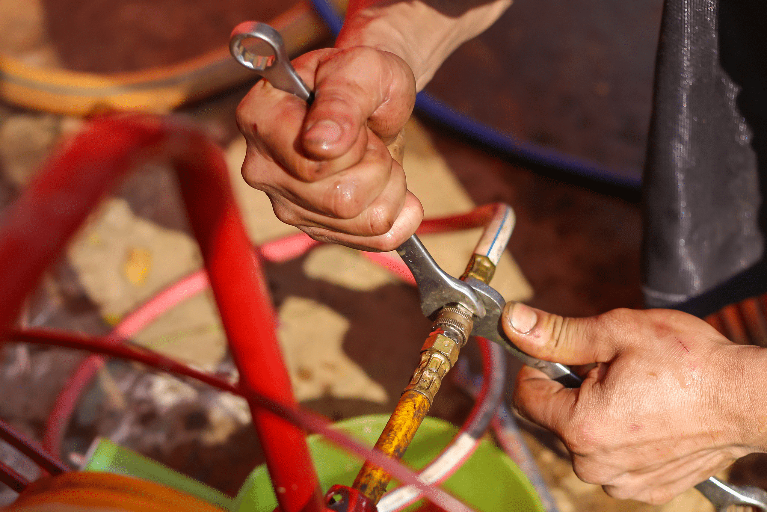 Man using two wrenches on spigot to attach hose.