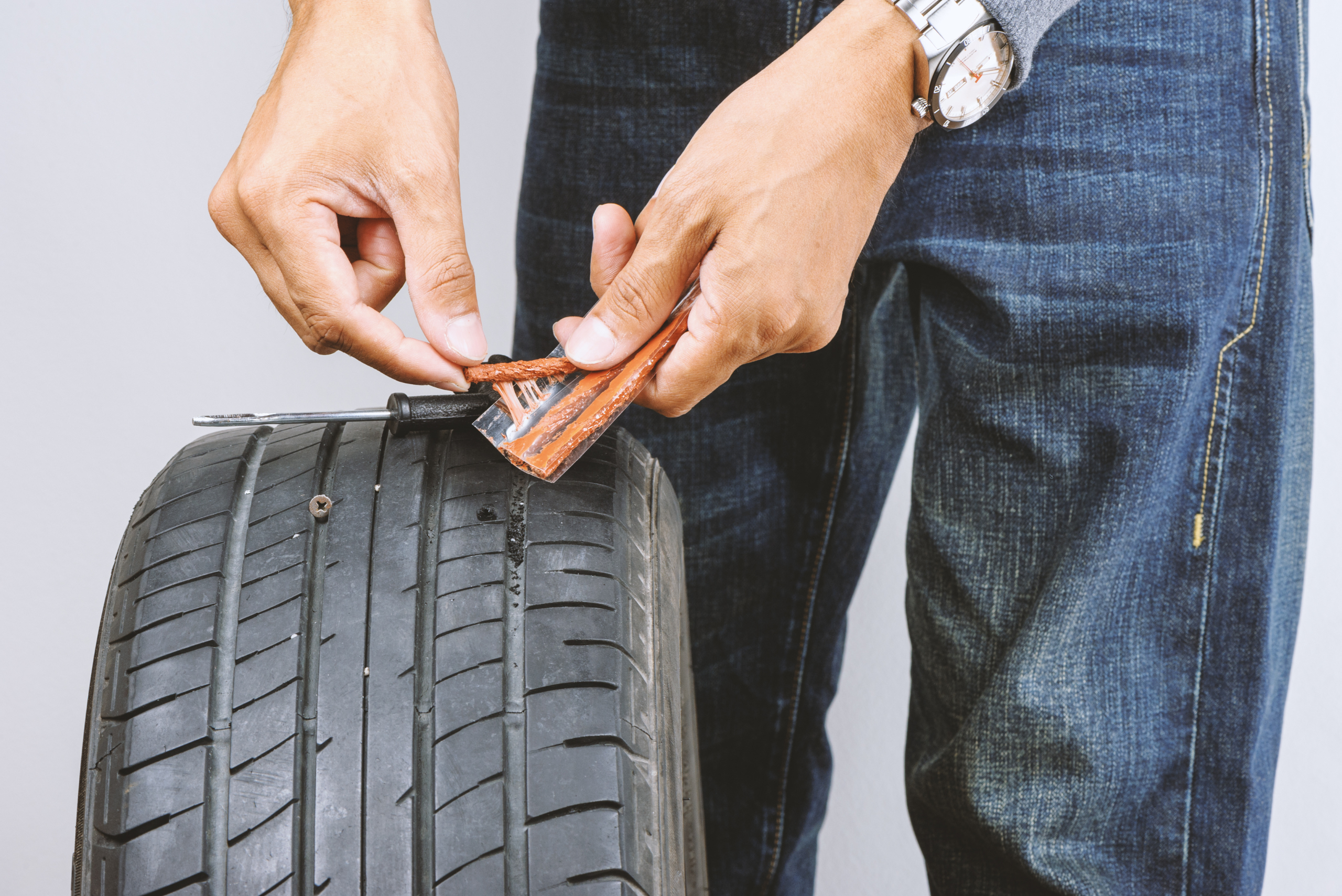 Man using a tire plug kit.