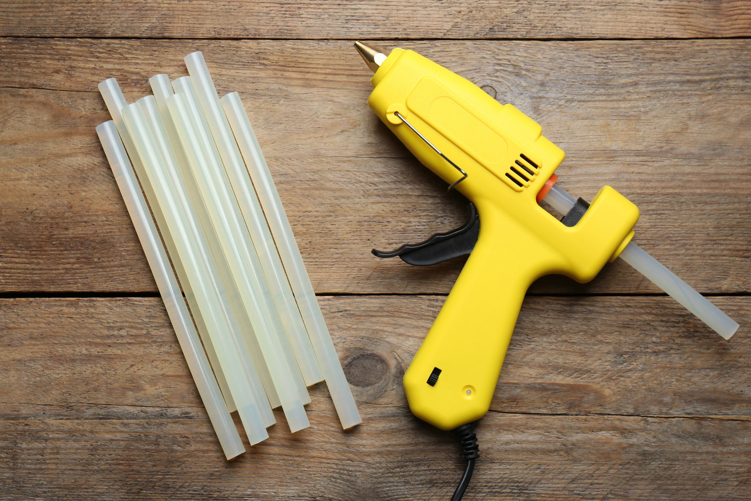 Hot glue gun on wooden background.