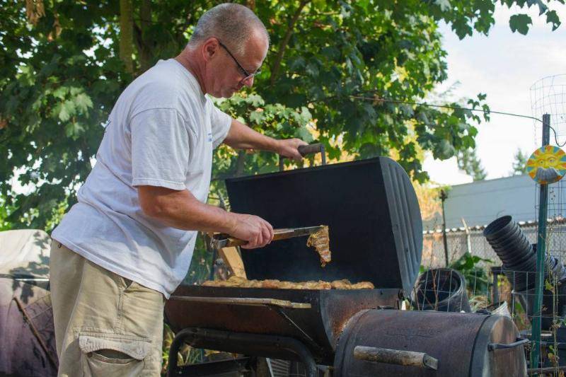 Man using a BBQ holding lid open.