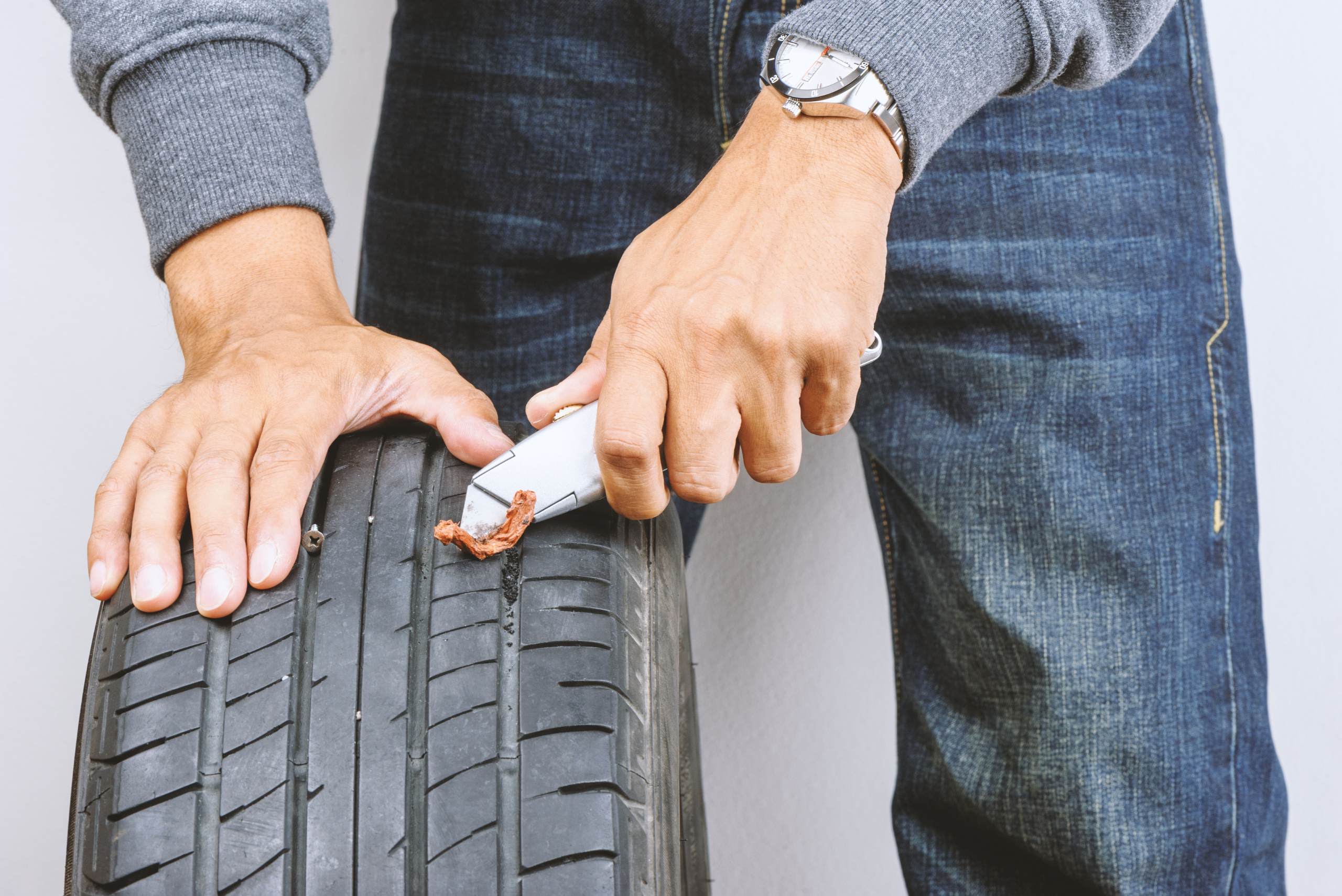 Man using a tire plug kit.