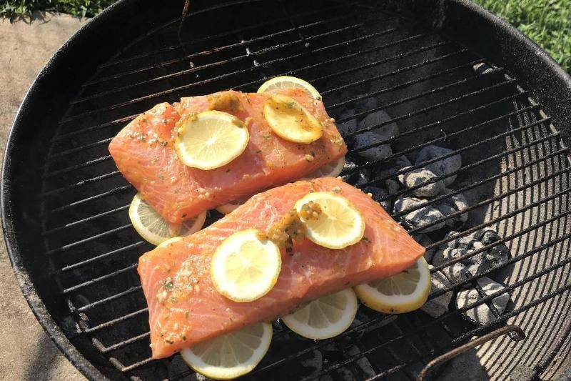 Slices of fish and lemon on grill.