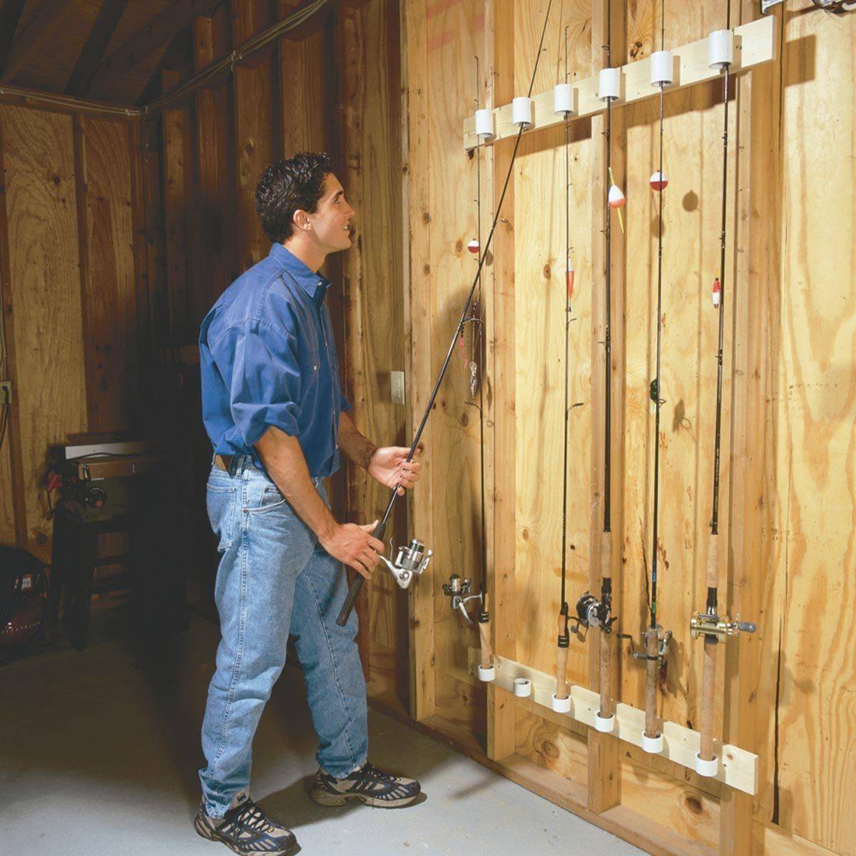 Man putting a fishing rod back up onto the wall mount.