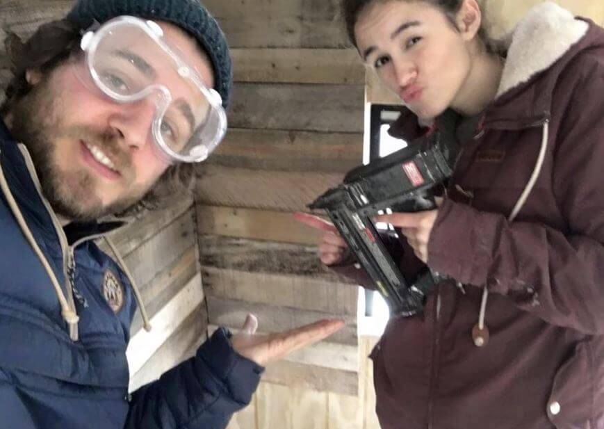 Couple posing for picture, man wearing eye protection while the woman hold a nail gun.