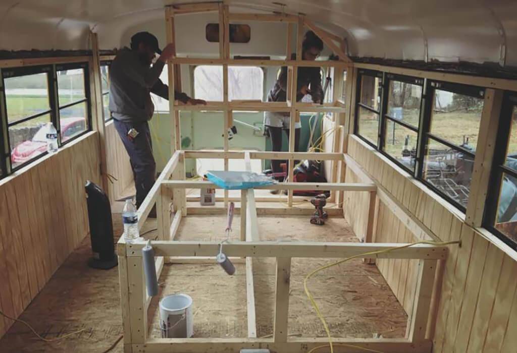 Couple building wood framing inside the bus.