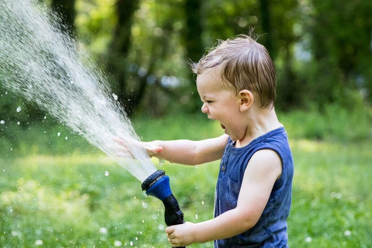 Kid playing with a water hose.