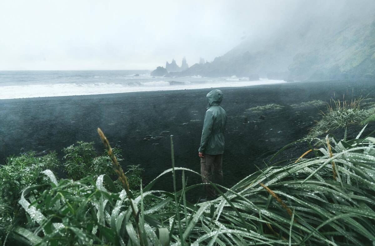 Person wearing rain coat standing on grass.