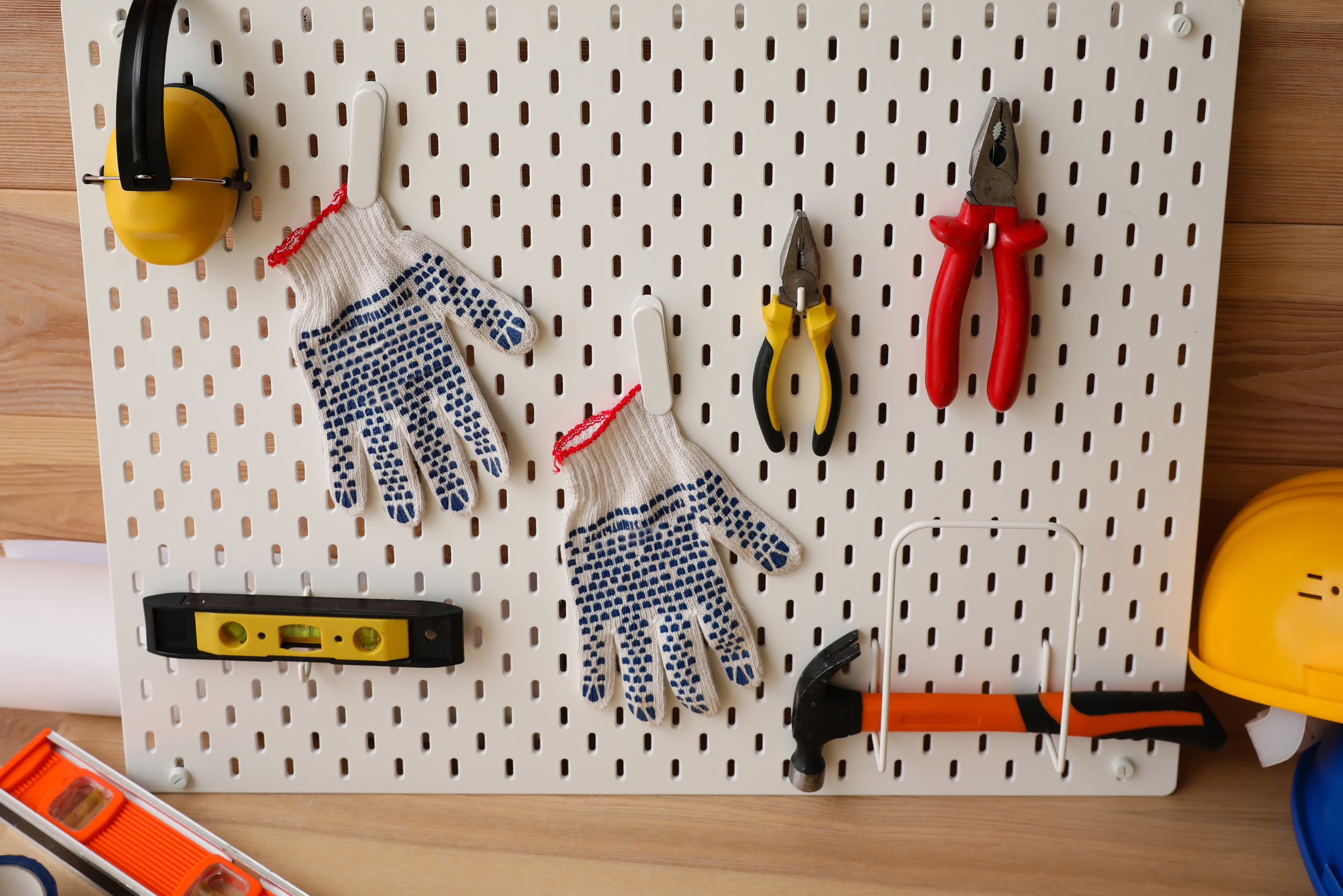 Pegboard with hooks hanging gloves and tools.