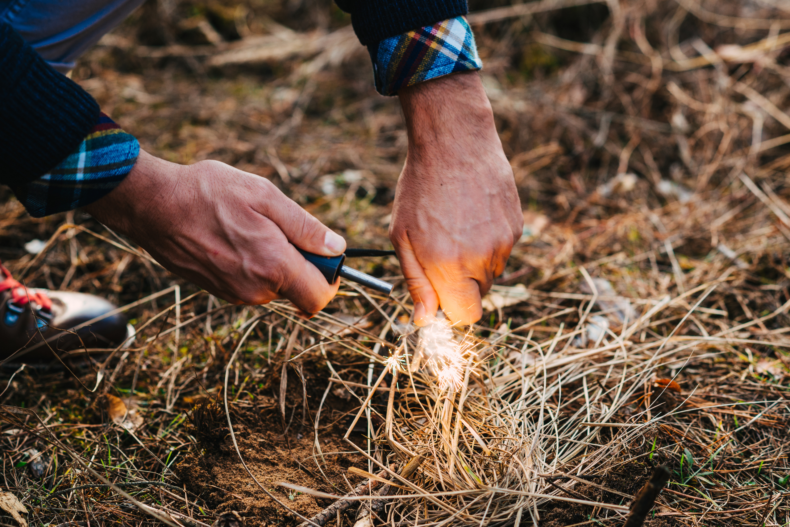 Person sparking a fire in dry sticks.