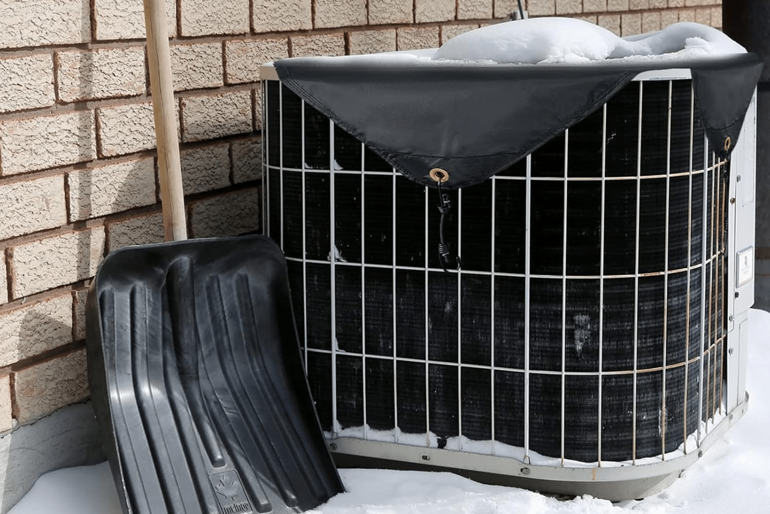 A/C unit in snow with black top cover.