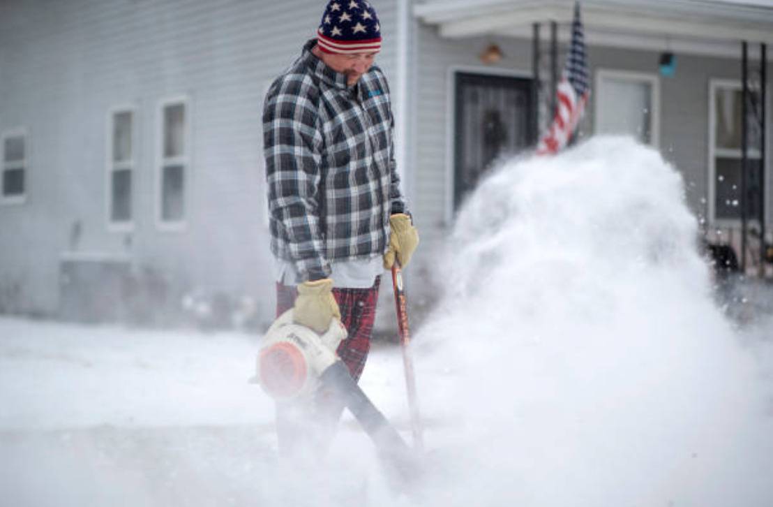 Person blowing snow off car.