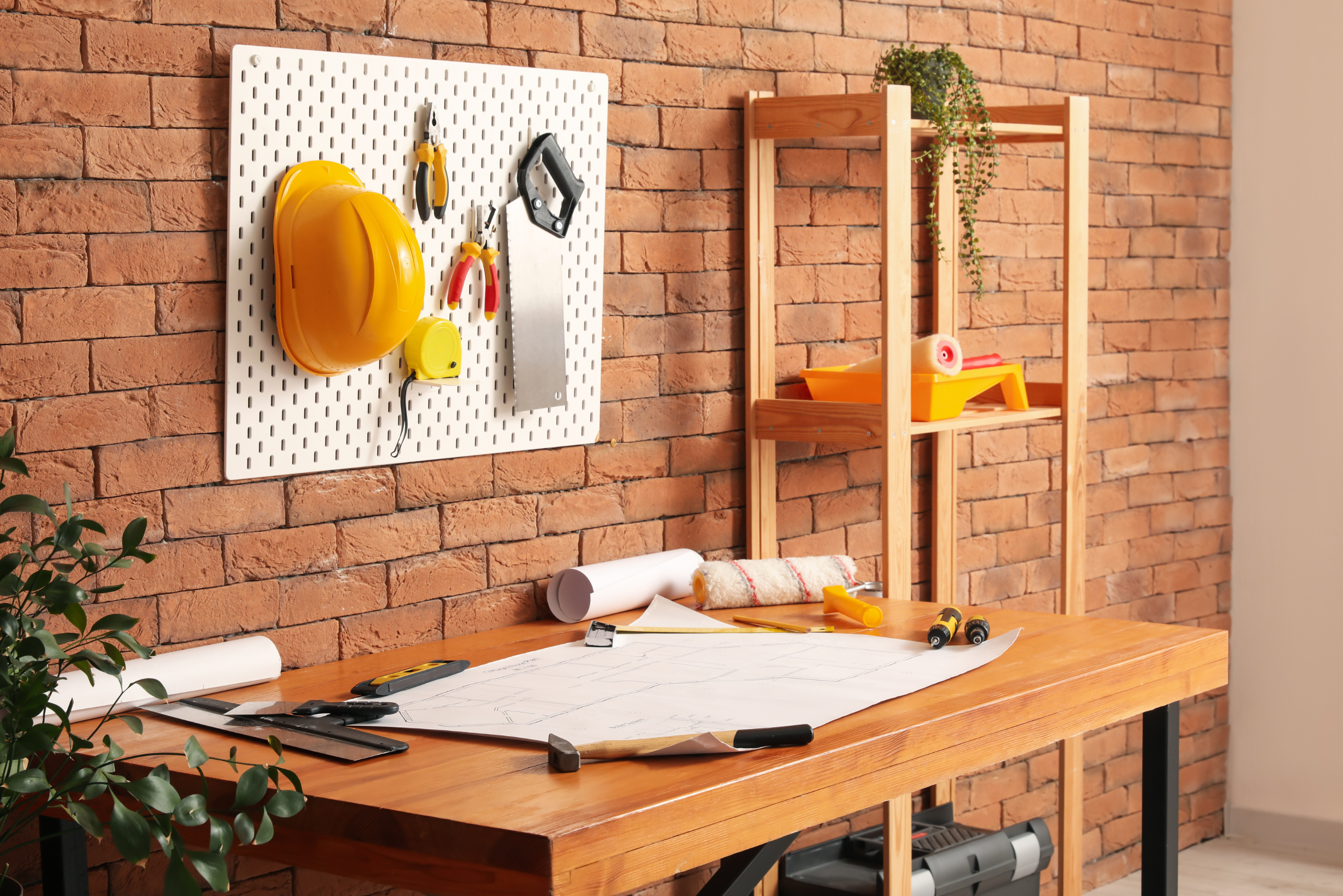 Work desk with pegboard holding hard hat and tools.