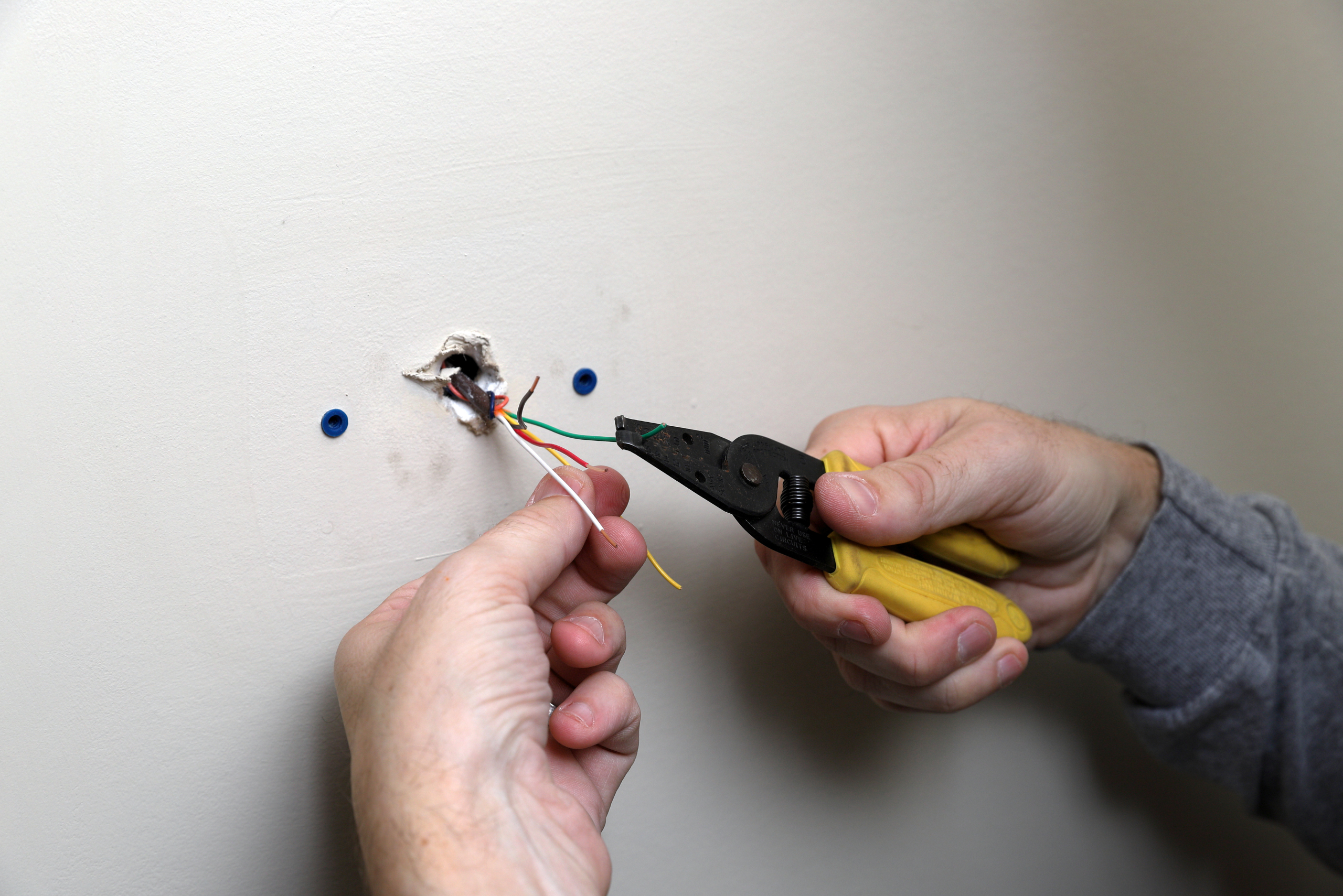 Pulling wires from the wall to install a new thermostat.