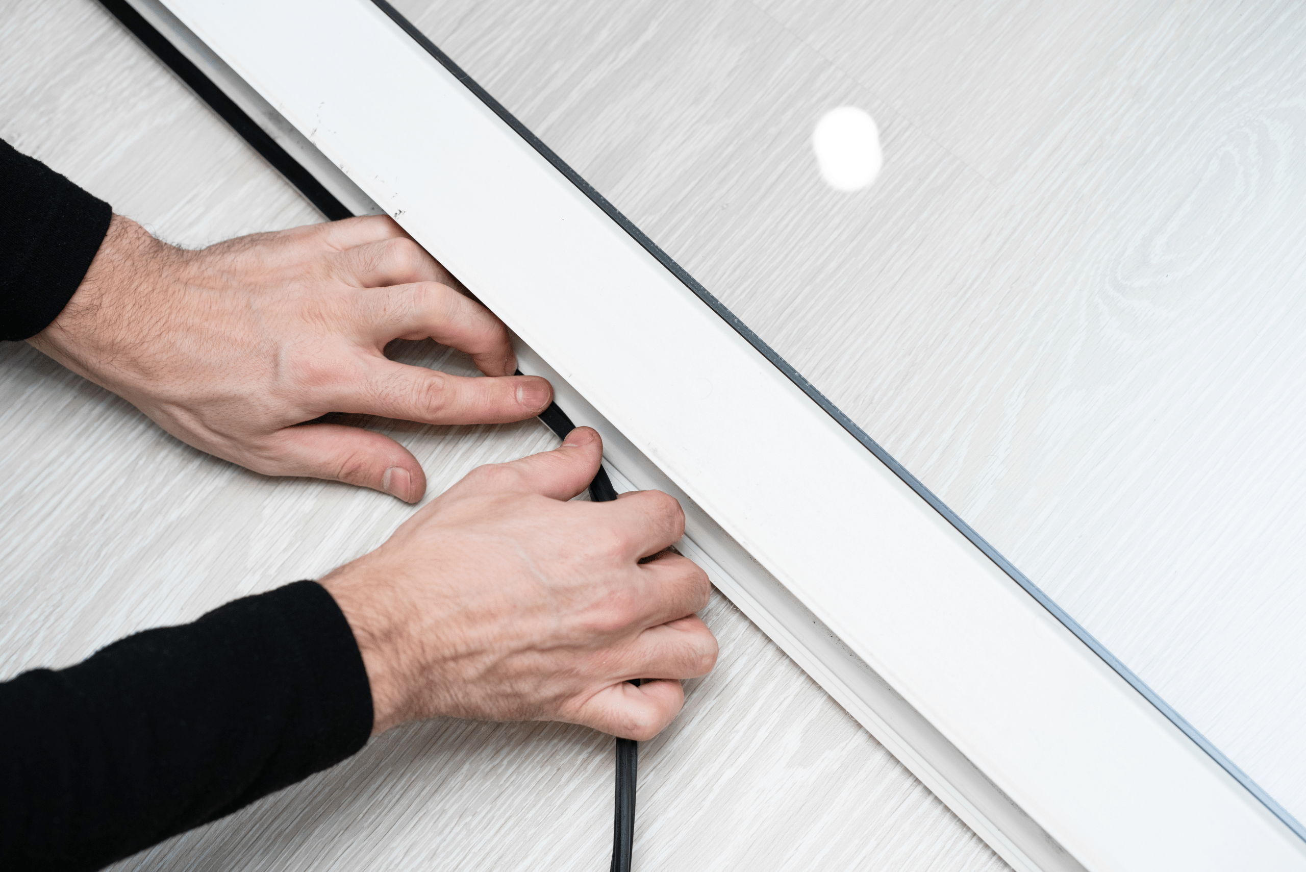 Person pushing in a window seal into window frame.