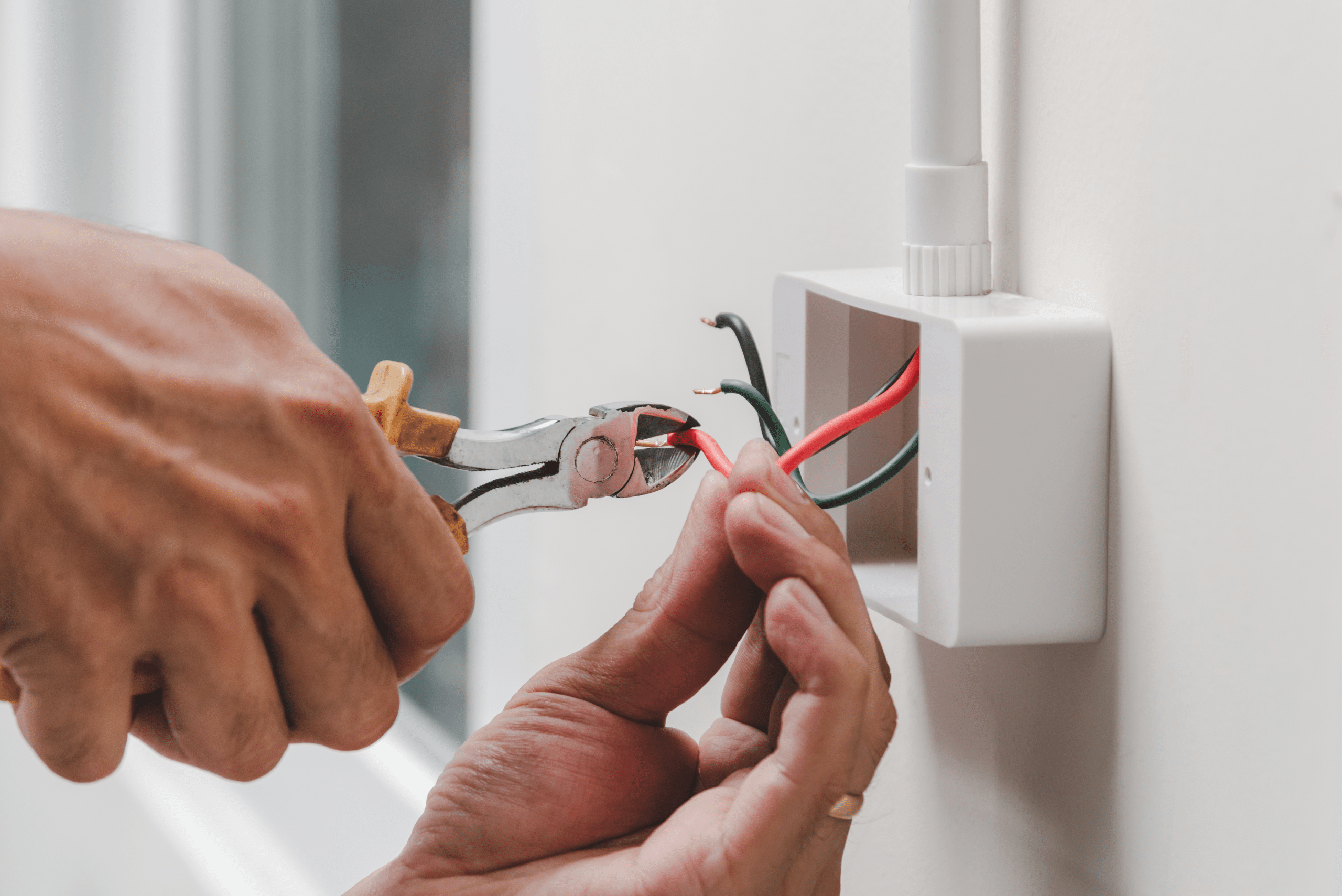 Person using cutters to cut outlet wires.