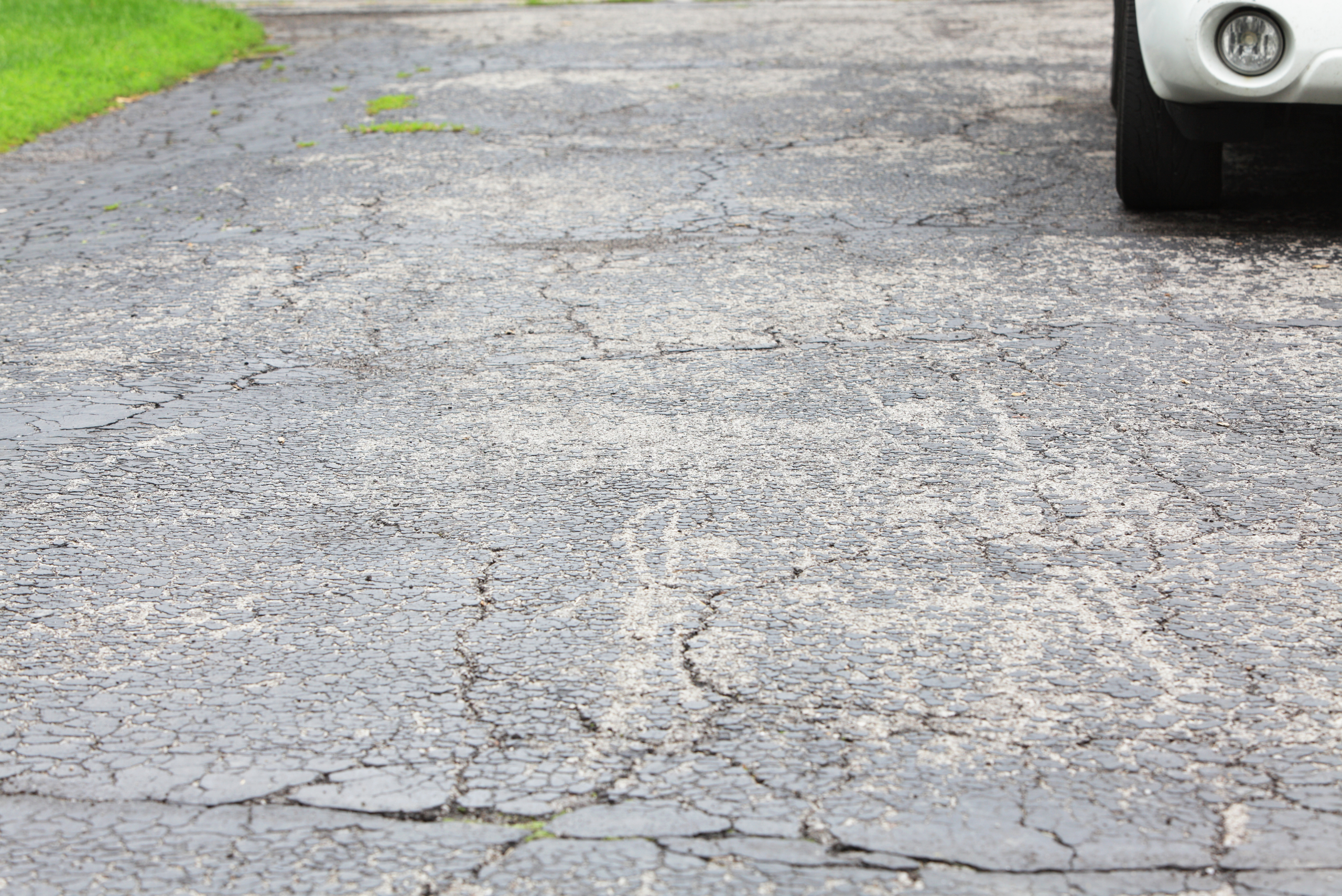 Asphalt driveway with many cracks forming.