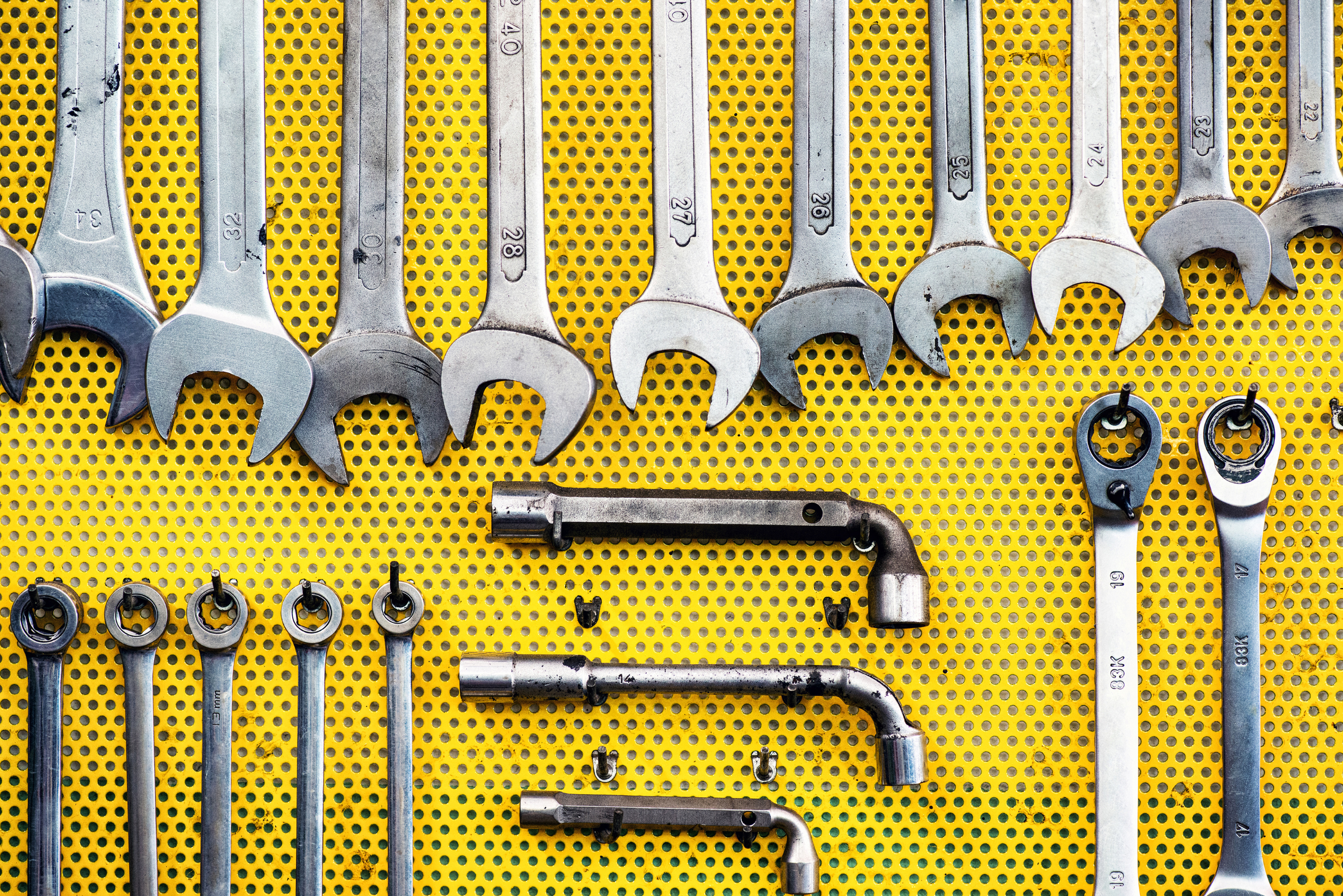 Yellow pegboard with tools on it.