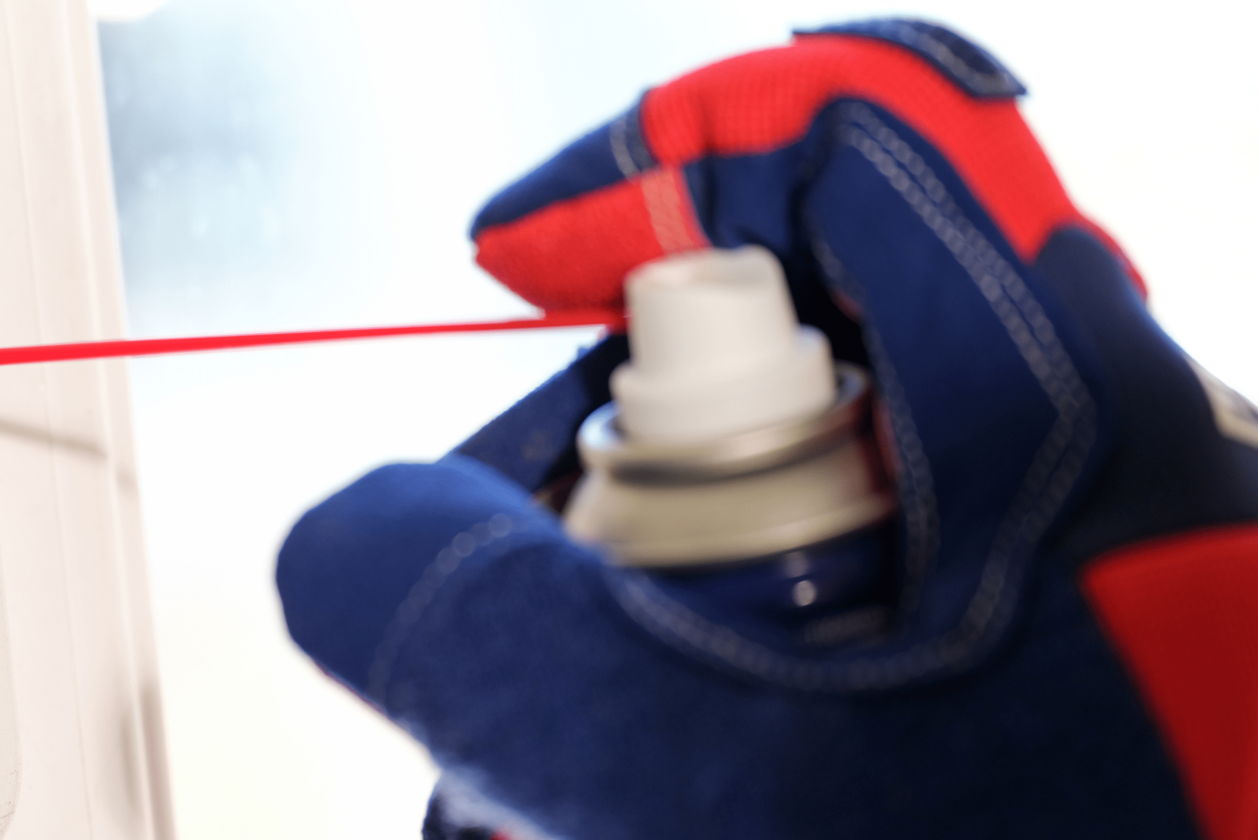 Closeup of someone's hand wearing gloves spraying WD-40.