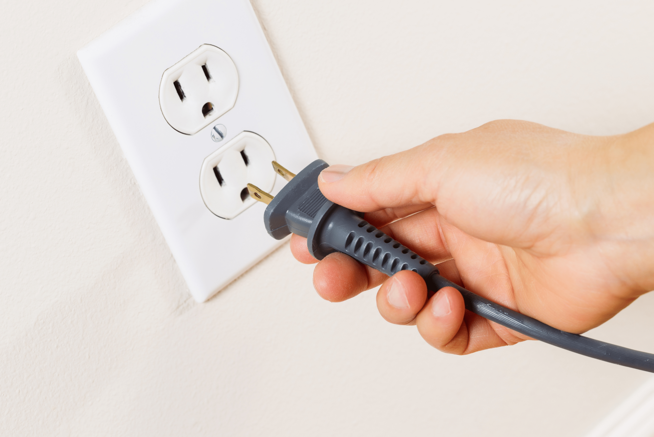 Person inserting a plug into a wall outlet.