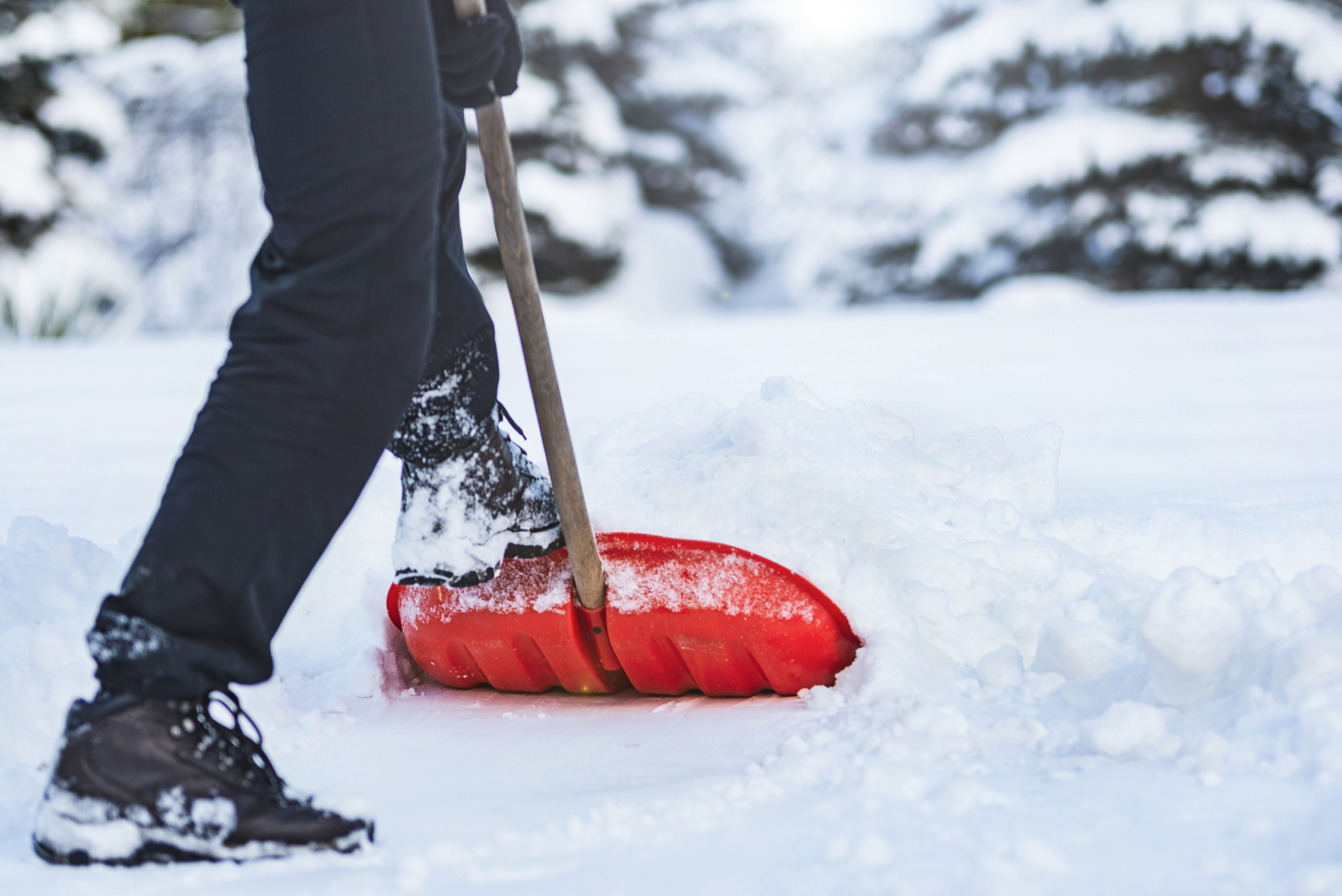 Person shoveling snow using their foot for leverage.