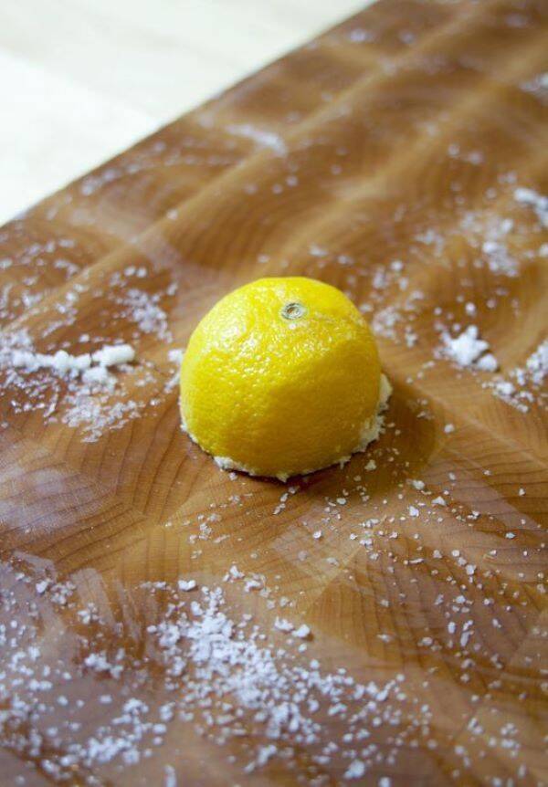 Half a lemon on wooden board with salt.