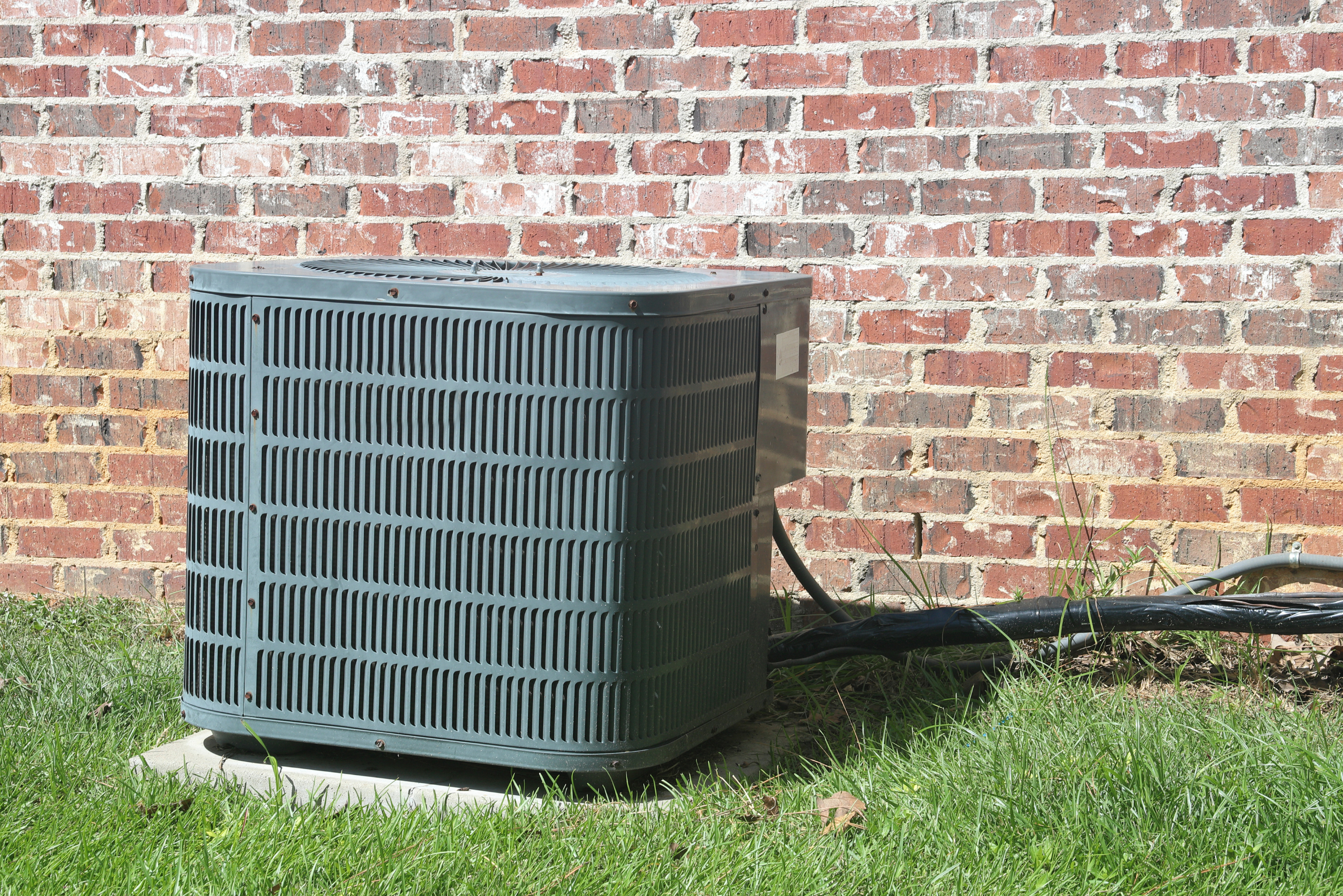 Green A/C unit in grassy yard.